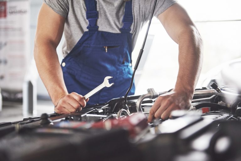muscular-car-service-worker-repairing-vehicle
